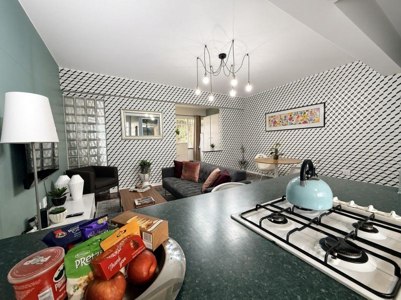 Open plan living and kitchen area featuring a gas cooktop, modern pendant lighting, and a unique glass block feature wall.