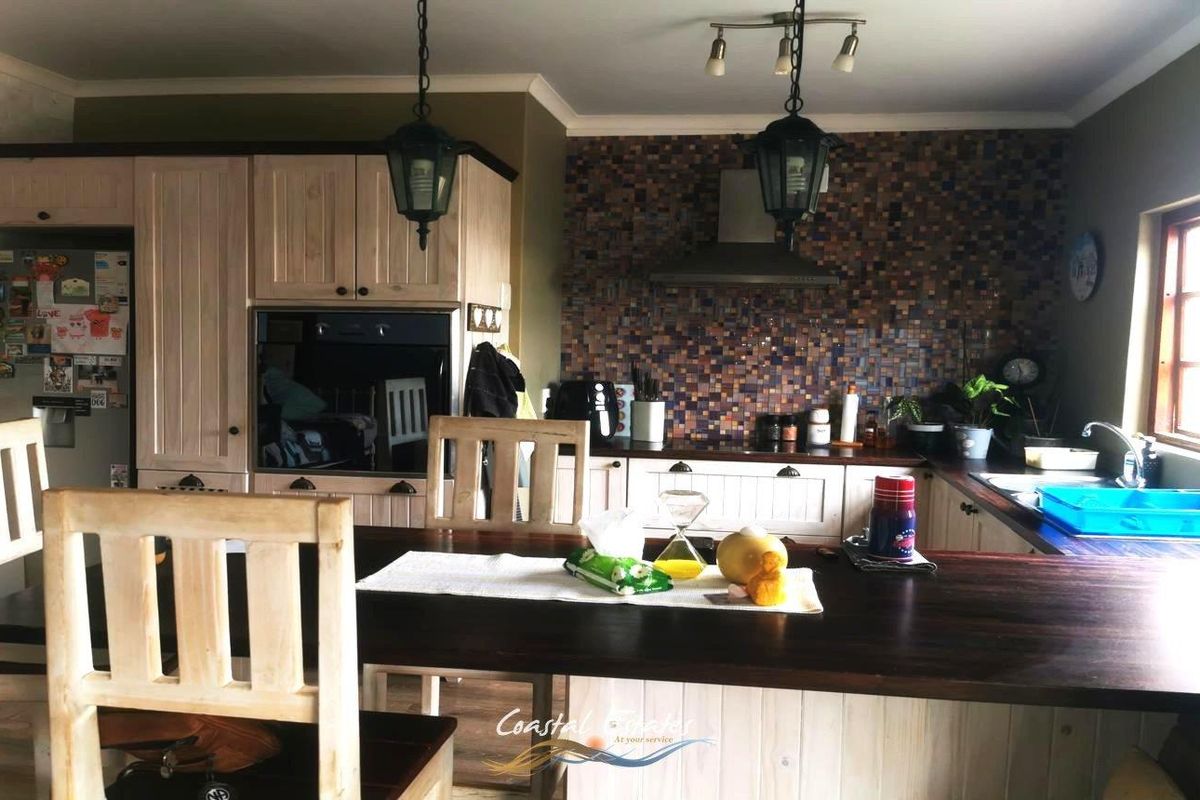 A kitchen featuring wooden cabinetry, a mosaic tile backsplash, a built-in oven, and an extractor fan, with an integrated breakfast bar.
