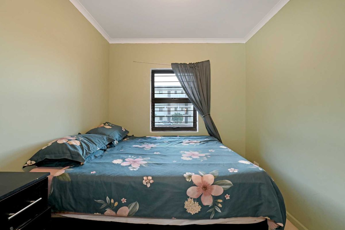A standard bedroom featuring a window with security bars and simple cove cornicing.