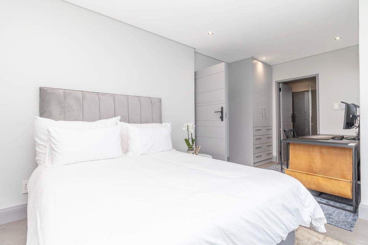 A modern, well-maintained bedroom featuring neutral tones, built-in cabinetry, recessed lighting, and an en-suite bathroom.