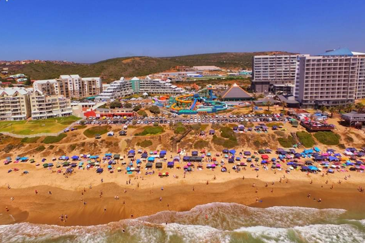 Aerial view of the coastal resort area featuring multi-story apartment buildings, a water park, and direct beach access.