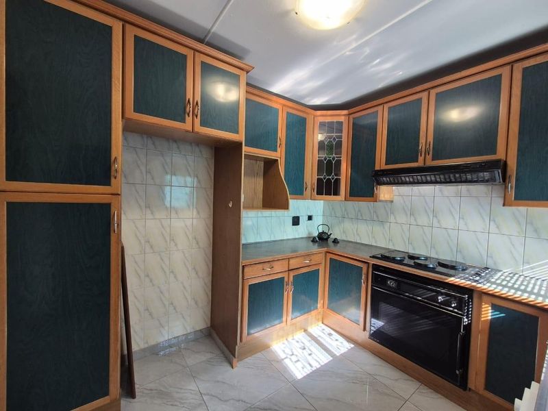 A functional kitchen featuring built-in cabinetry, a tiled backsplash, and integrated oven and hob, offering a solid foundation for modern updates.