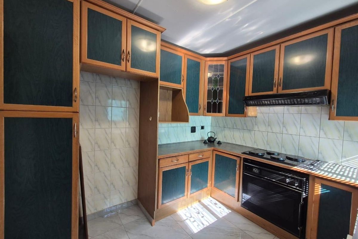 A functional kitchen featuring built-in cabinetry, a tiled backsplash, and integrated oven and hob, offering a solid foundation for modern updates.