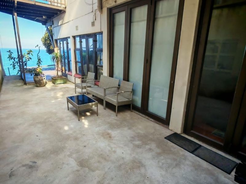 Covered patio area featuring concrete flooring and large sliding glass doors, offering direct access to the outdoor space with ocean views.
