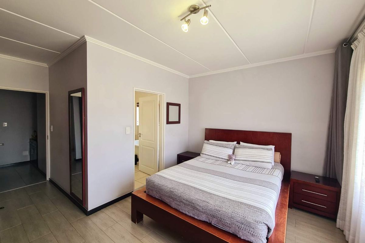 A well-maintained bedroom featuring tiled flooring, coved ceilings, and neutral wall finishes, providing a clean and functional living space.