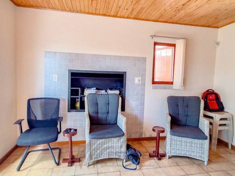 Living room featuring a built-in fireplace with tiled surround, timber ceiling, and tiled flooring.