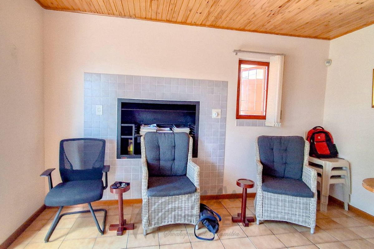 Living room featuring a built-in fireplace with tiled surround, timber ceiling, and tiled flooring.