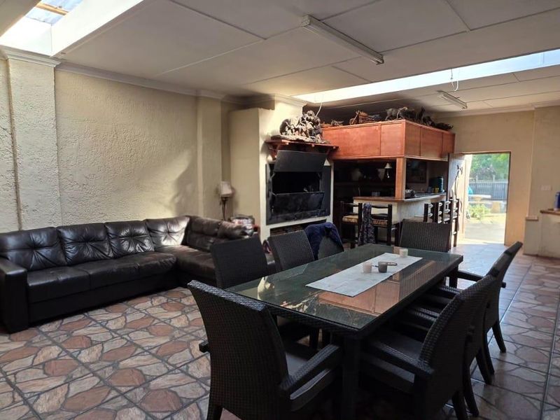 Spacious covered patio area featuring a built-in fireplace, bar, and pizza oven, with tiled flooring and skylights providing natural light.