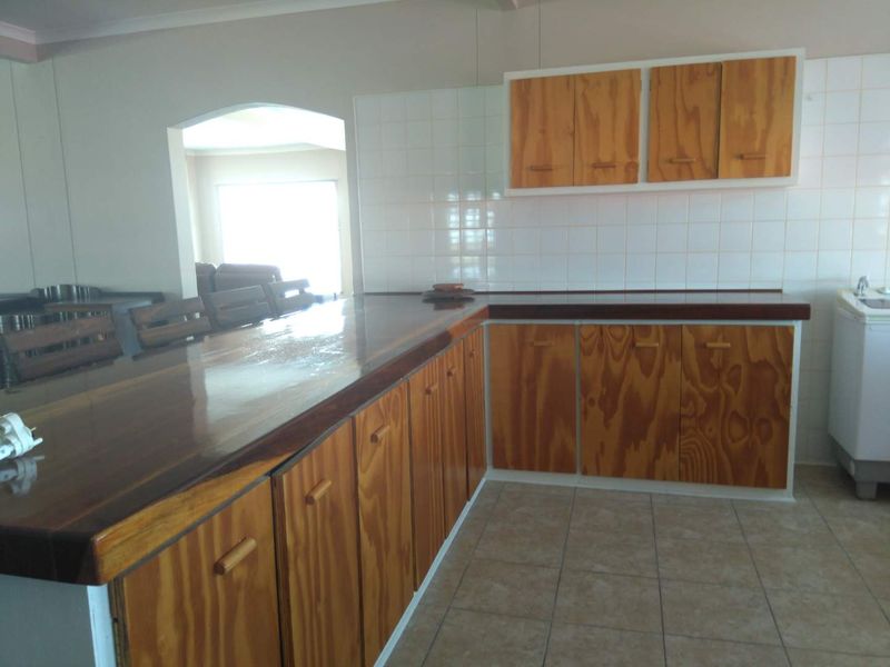 A dated kitchen featuring wooden cabinetry, tiled backsplash, and a wooden breakfast bar counter, offering potential for a modern renovation.