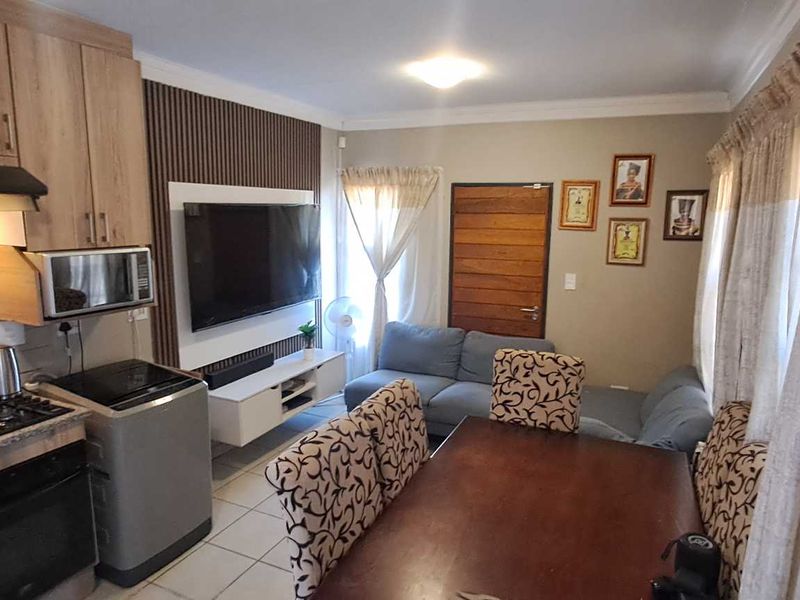 Open-plan living area featuring a modern kitchen with built-in cabinetry, gas hob, and oven, seamlessly flowing into a comfortable lounge and dining space.