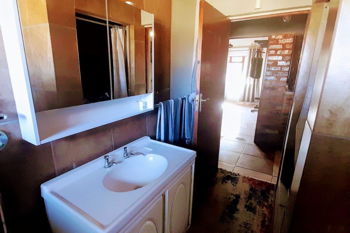 A functional bathroom featuring a vanity cabinet with an integrated basin and a mirrored medicine cabinet, finished with brown wall tiles.