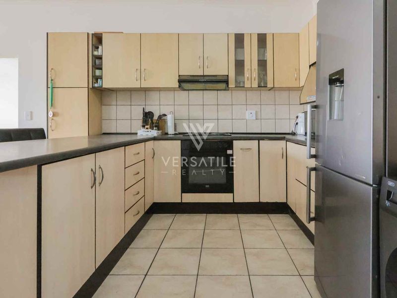 A functional kitchen featuring laminate cabinetry, built-in oven, extractor fan, and tiled flooring, offering a practical layout for daily meal preparation.