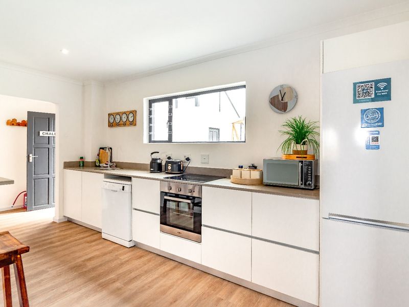 Modern kitchen featuring sleek white cabinetry, integrated appliances, built-in oven, electric hob, and durable laminate flooring.