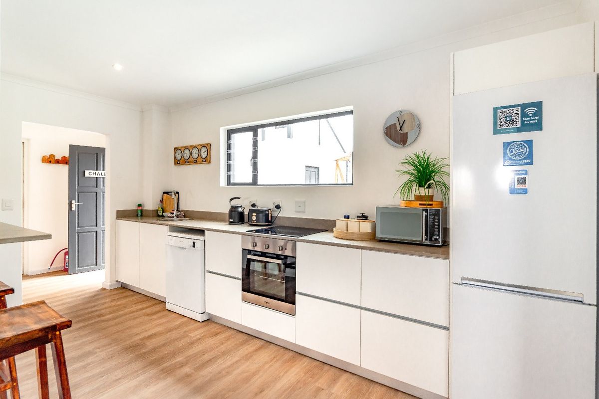 Modern kitchen featuring sleek white cabinetry, integrated appliances, built-in oven, electric hob, and durable laminate flooring.