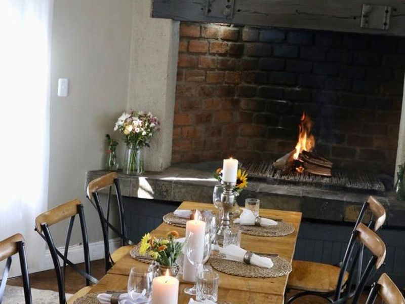 A cozy dining area featuring a prominent brick fireplace with a rustic timber mantelpiece and stone hearth, creating a warm and inviting atmosphere.