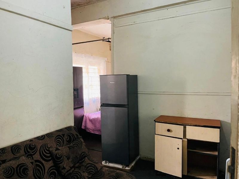 A living area showing significant wear to wall and ceiling finishes, requiring cosmetic renovation and repair to improve the overall condition.