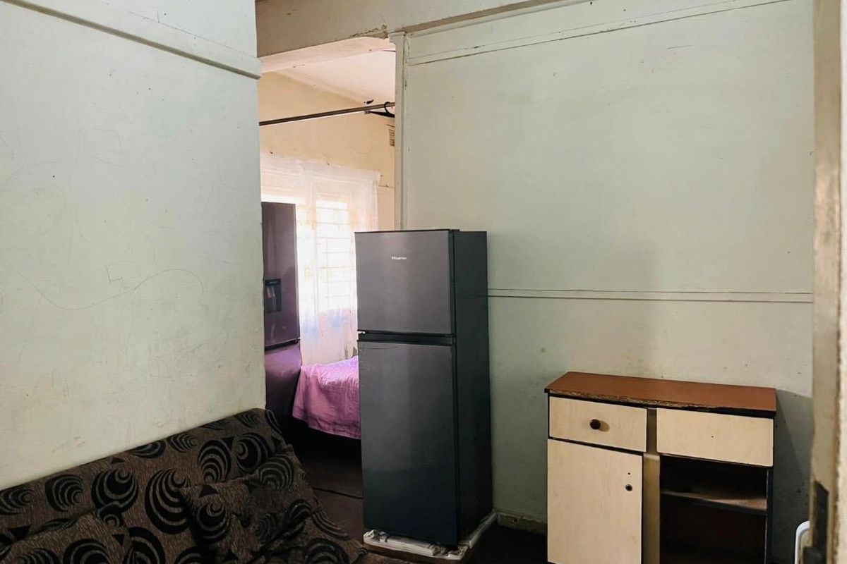 A living area showing significant wear to wall and ceiling finishes, requiring cosmetic renovation and repair to improve the overall condition.