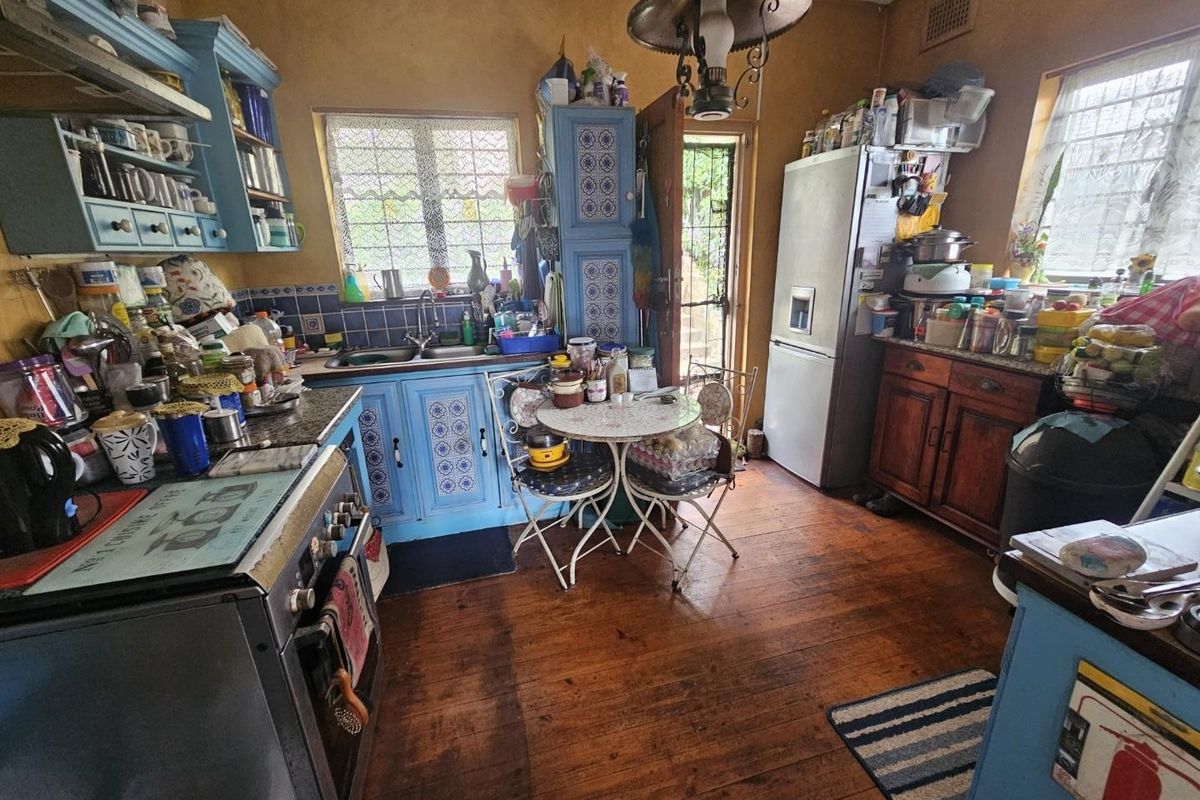 A dated kitchen featuring hardwood flooring, blue cabinetry, and a tiled backsplash, offering potential for a modern renovation.