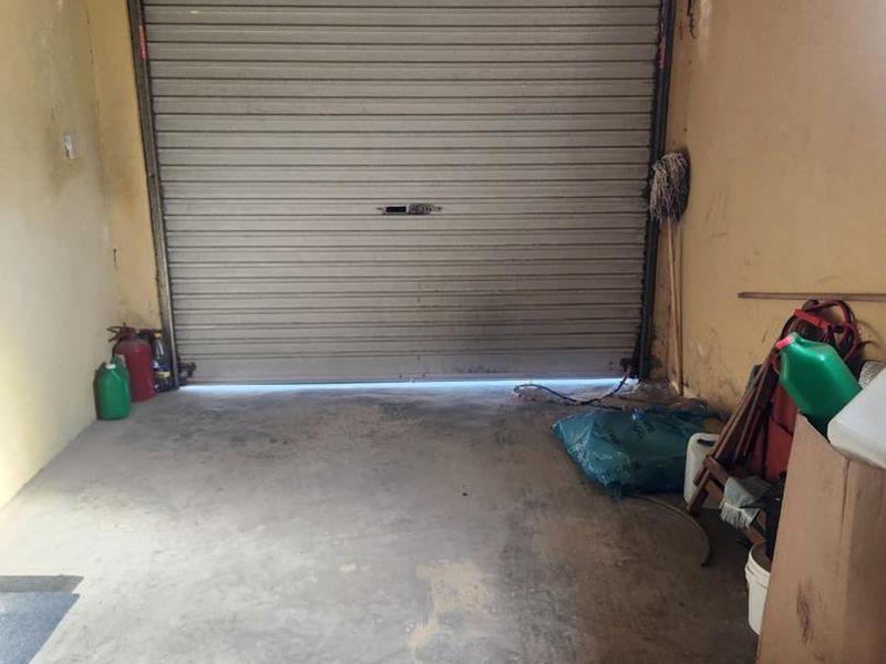 A functional garage space featuring a secure roller shutter door and durable concrete flooring, providing ample storage or vehicle parking potential.