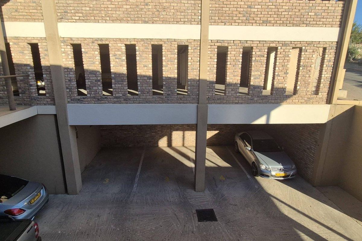 A covered parking area featuring brick facade detailing and concrete flooring, providing secure off-street parking for the office property.