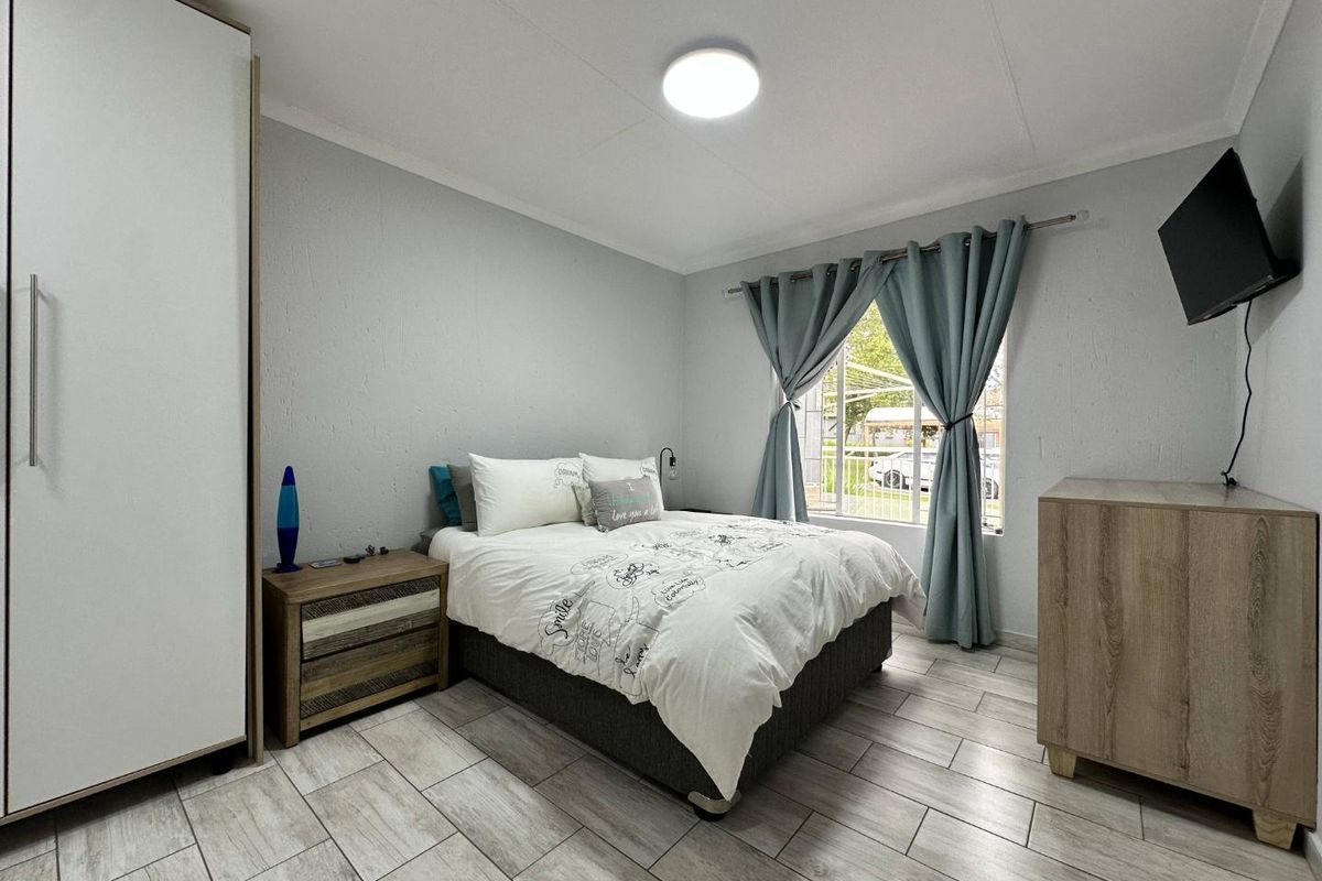 A well-maintained bedroom featuring tiled flooring, a built-in wardrobe, and a window providing natural light.