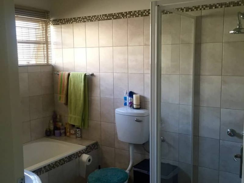 A functional bathroom featuring a tiled shower enclosure, a built-in bathtub, a toilet, and a vanity basin with neutral wall tiling.
