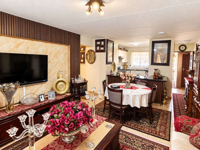 An open-plan living and dining area featuring decorative wall paneling, a kitchen breakfast bar, and integrated cabinetry, creating a cohesive and functional living space.