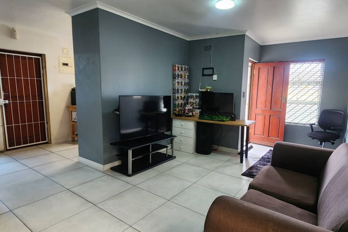 Open-plan living area featuring tiled flooring, neutral wall tones, and direct access to exterior doors with security gates.