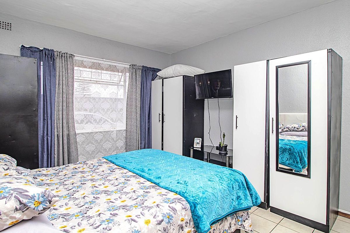 A bedroom featuring tiled flooring and a window with curtain tracks.