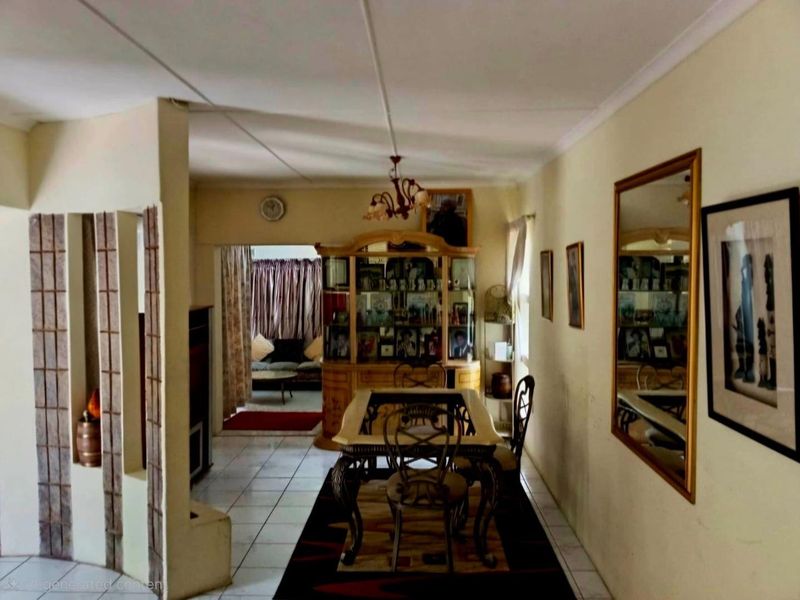 Dining area featuring tiled flooring and a decorative room divider, leading into an adjacent living space.