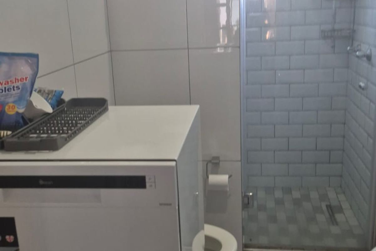 A functional bathroom featuring a glass-enclosed shower with subway tile finishes and modern laminate flooring.