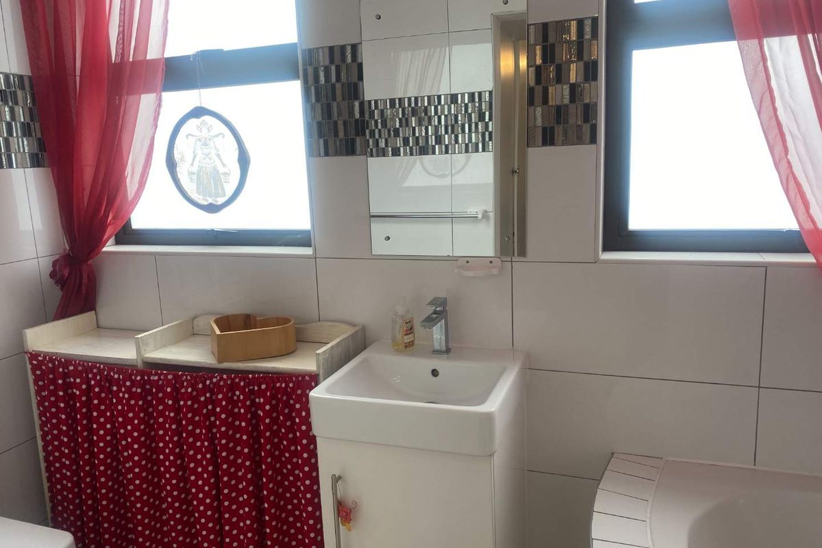 A functional bathroom featuring a modern vanity with a basin, tiled walls with decorative mosaic accents, and a built-in bathtub.