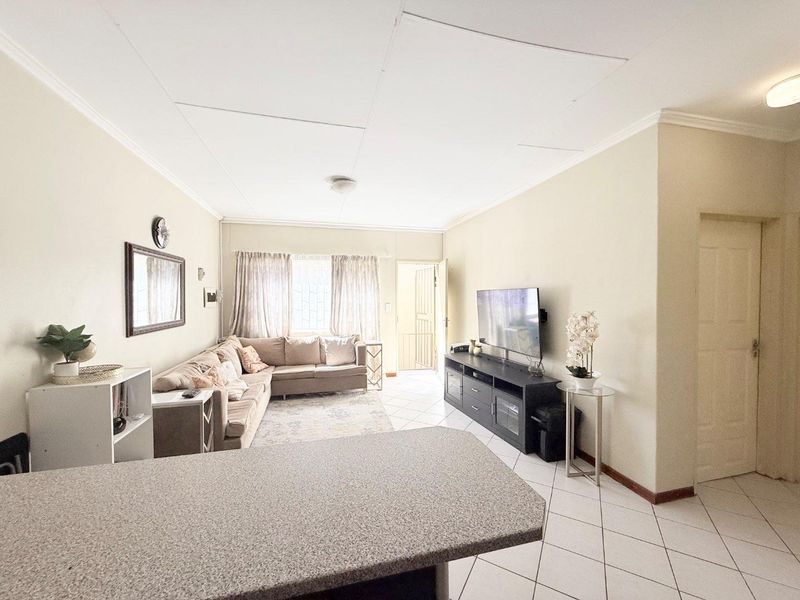 Open plan living area featuring tiled flooring and a breakfast counter, providing a functional space that connects to the entrance and kitchen area.