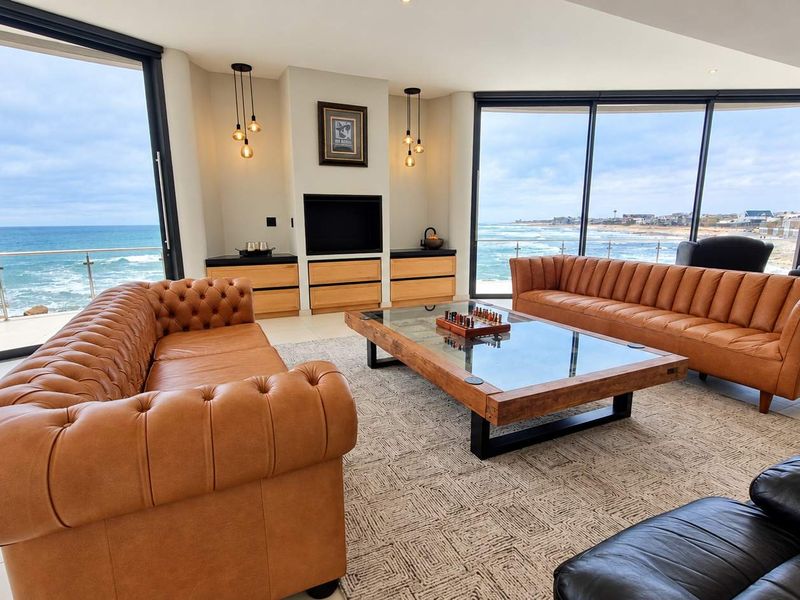 Spacious penthouse living area featuring floor-to-ceiling glass walls with panoramic ocean views, sleek built-in cabinetry, and modern tiled flooring.