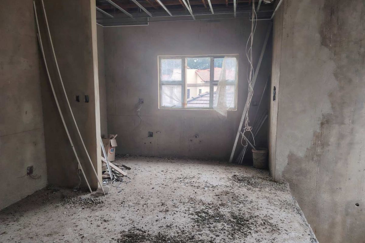 An unfinished bedroom space in shell condition, featuring exposed ceiling grid, plastered walls, and electrical wiring, ready for final fit-out and finishes.
