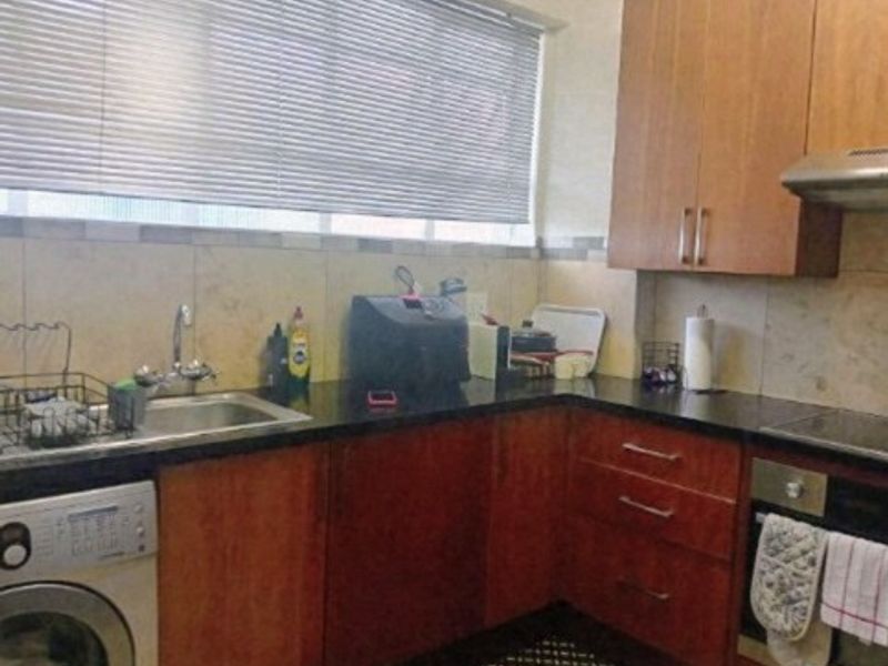 A functional kitchen featuring wood-finish cabinetry, dark granite countertops, a built-in oven with extractor fan, and a tiled backsplash.