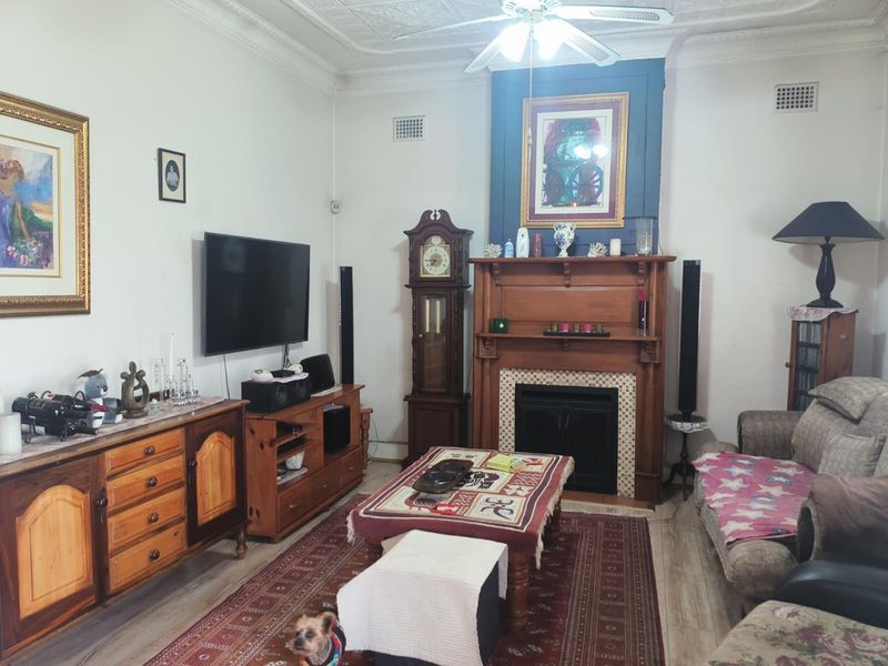 A traditional living room featuring a prominent timber fireplace mantel, decorative ceiling detailing, and ornate cornicing, providing a classic character feel.