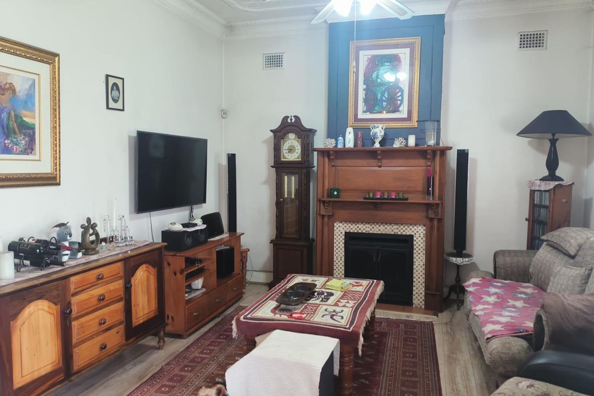 A traditional living room featuring a prominent timber fireplace mantel, decorative ceiling detailing, and ornate cornicing, providing a classic character feel.