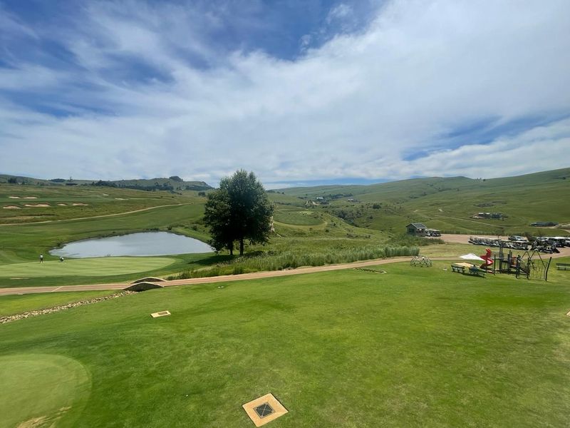 A scenic elevated view overlooking a well-maintained golf course, featuring a pond, rolling green hills, and landscaped recreational areas.