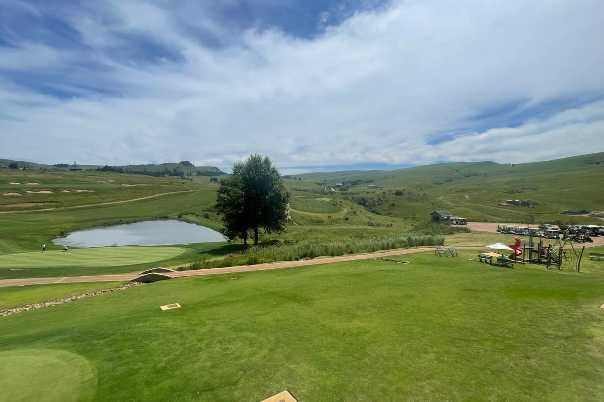 A scenic elevated view overlooking a well-maintained golf course, featuring a pond, rolling green hills, and landscaped recreational areas.