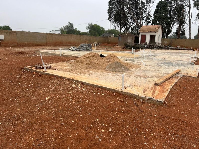 Vacant residential land featuring a concrete slab foundation, perimeter boundary wall, and existing plumbing rough-ins, ready for further development.