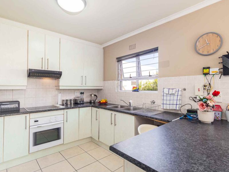 Functional kitchen featuring white cabinetry, dark laminate countertops, tiled backsplash, and built-in oven with extractor fan.