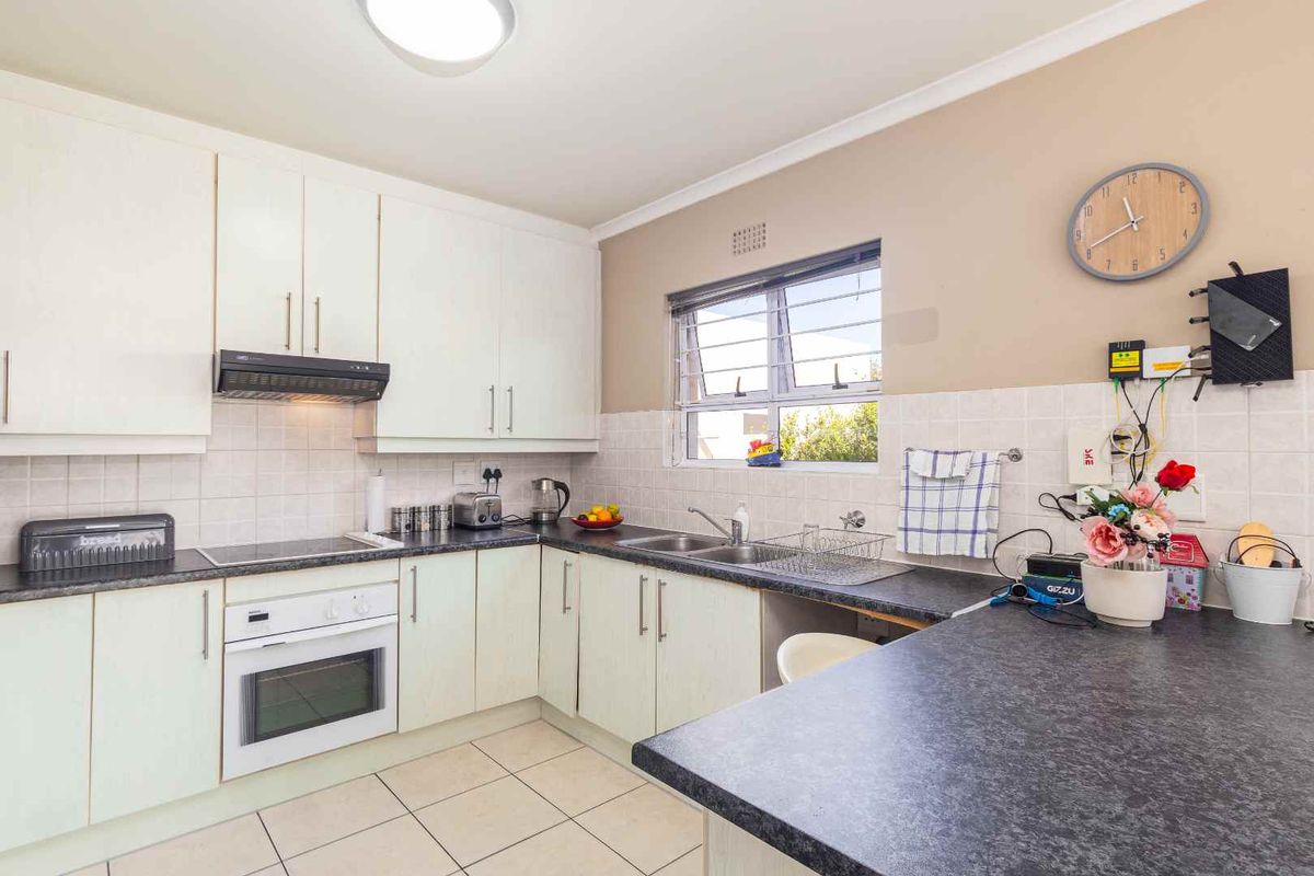 Functional kitchen featuring white cabinetry, dark laminate countertops, tiled backsplash, and built-in oven with extractor fan.
