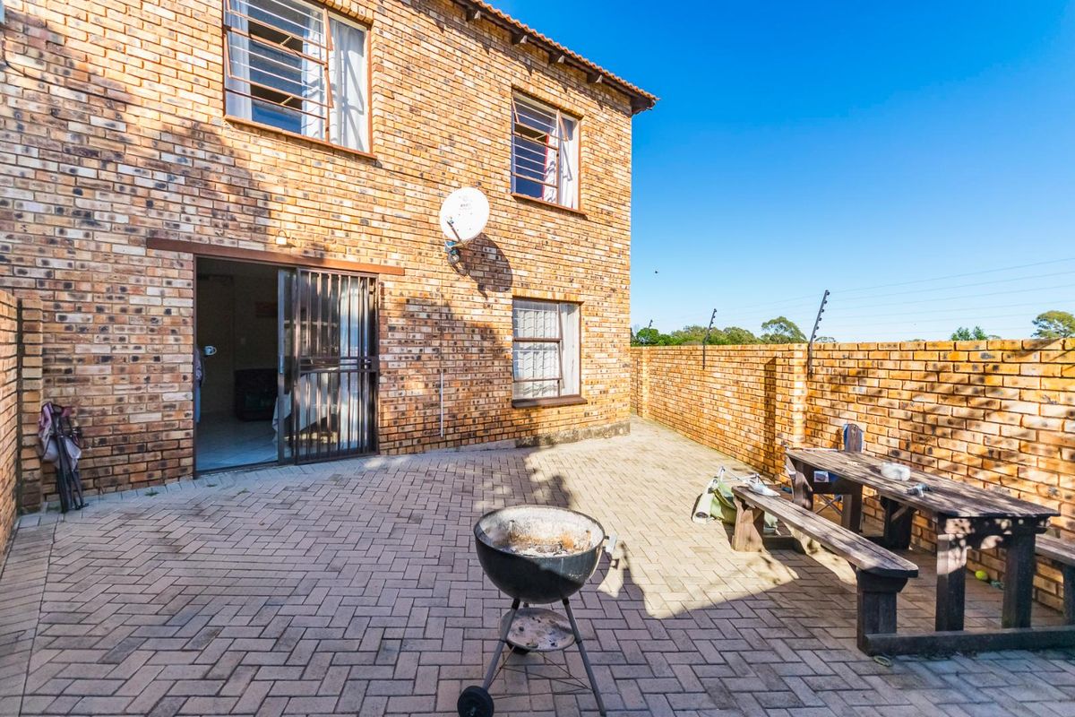 A private rear courtyard featuring paved flooring, face-brick walls, and a secure sliding door entrance to the apartment.