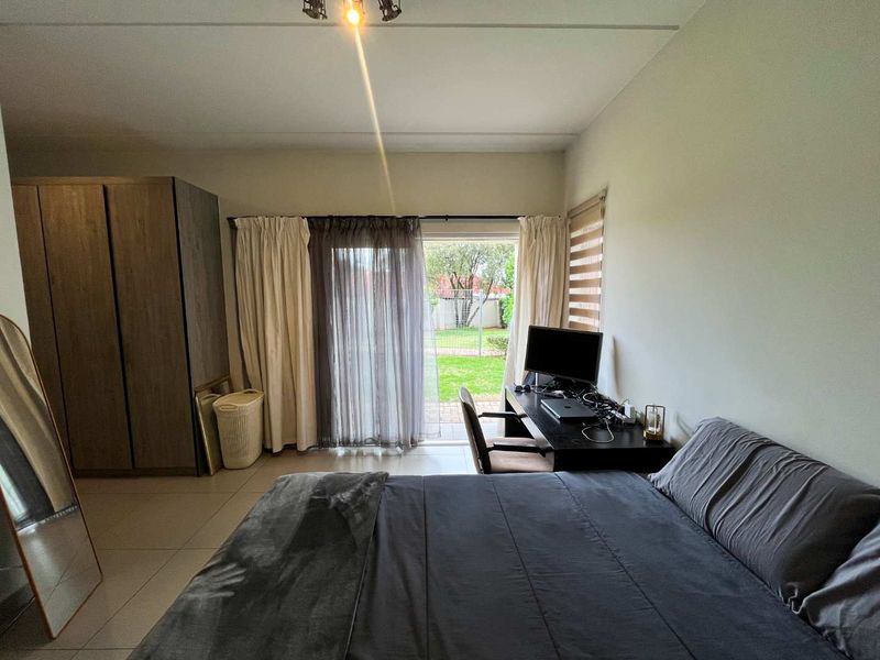A bedroom featuring tiled flooring, a built-in cupboard, and a sliding glass door providing direct access to the rear garden area.