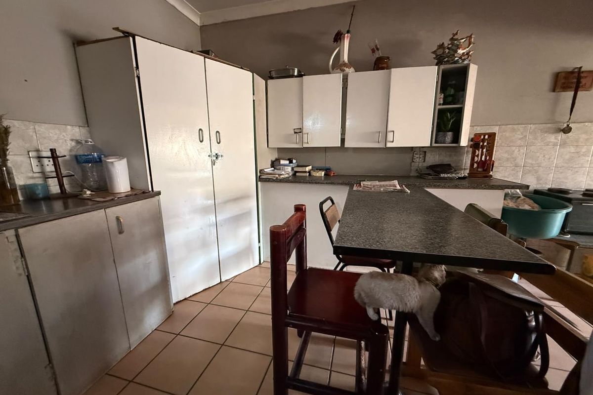 A functional kitchen featuring built-in cabinetry, laminate countertops, and tiled flooring, offering potential for modernization and aesthetic updates.