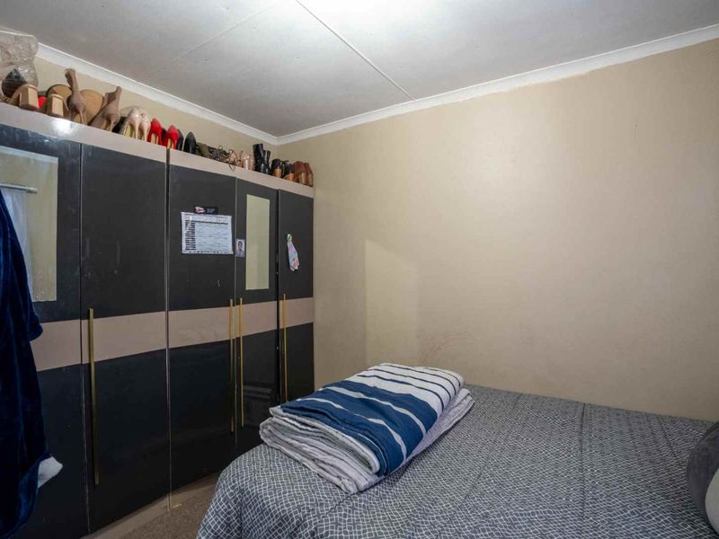 A bedroom featuring a large built-in wardrobe with integrated mirrors and ample storage space.