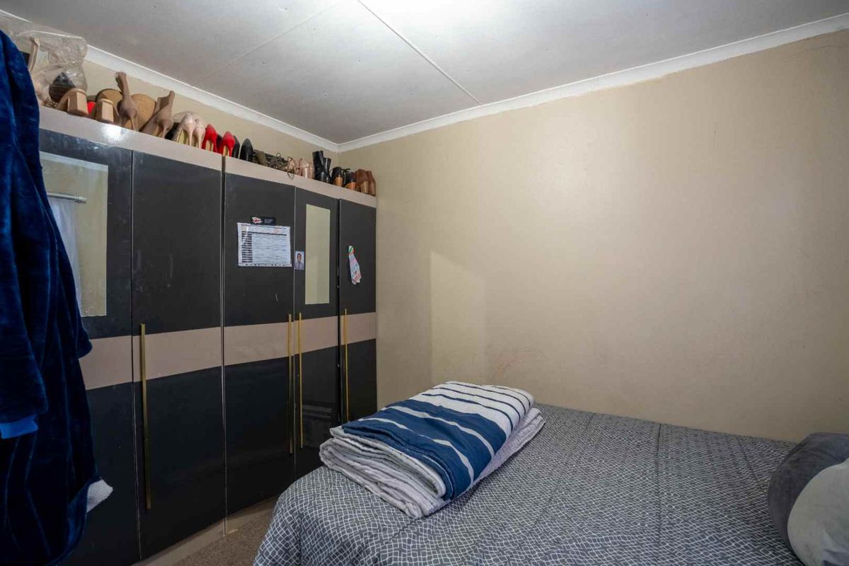 A bedroom featuring a large built-in wardrobe with integrated mirrors and ample storage space.