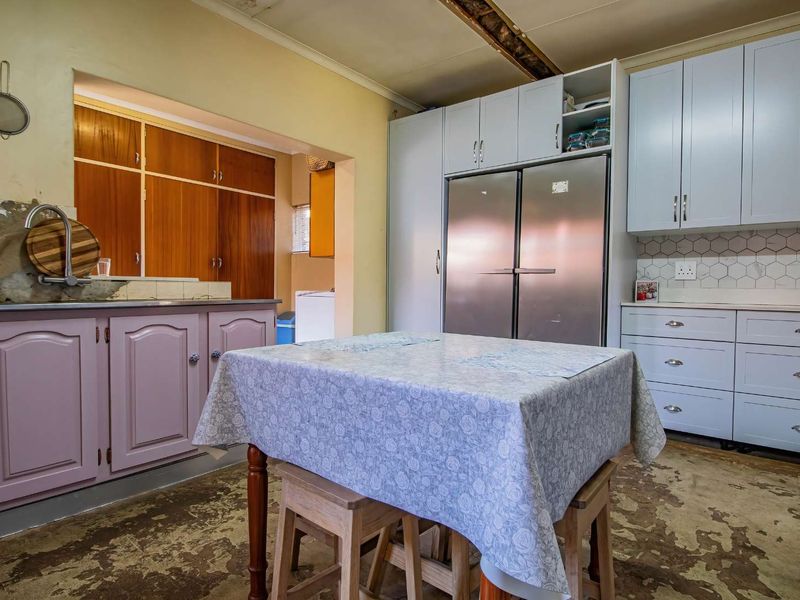 Kitchen featuring built-in cabinetry, a hexagonal tile backsplash, and a stainless steel sink, requiring renovation to address ceiling and flooring condition.