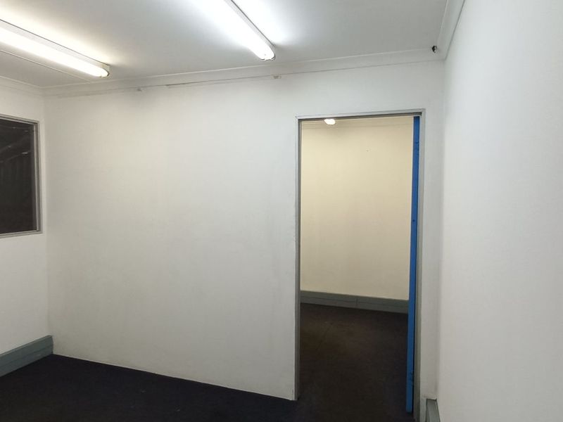 A clean, empty office space featuring neutral white walls, carpeted flooring, and fluorescent lighting, suitable for a professional workspace or administrative area.